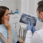 Dentist showing a dental X-ray to a woman with tooth pain.