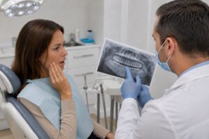 Dentist showing a dental X-ray to a woman with tooth pain.