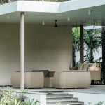 Modern outdoor patio with wicker furniture surrounded by greenery