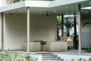 Modern outdoor patio with wicker furniture surrounded by greenery