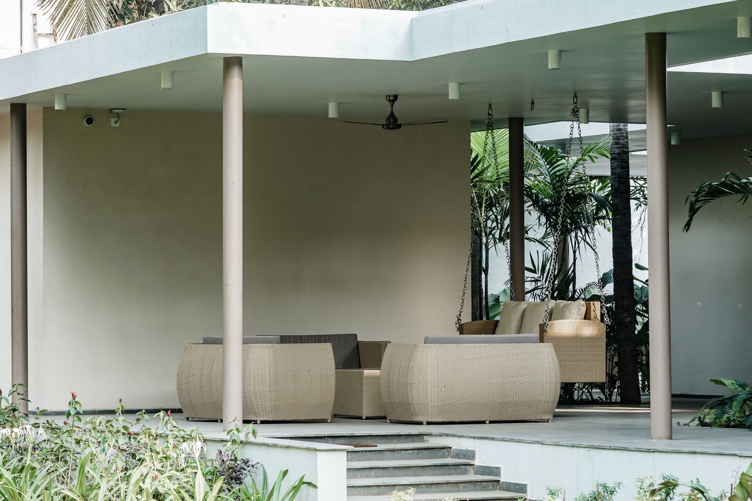 Modern outdoor patio with wicker furniture surrounded by greenery