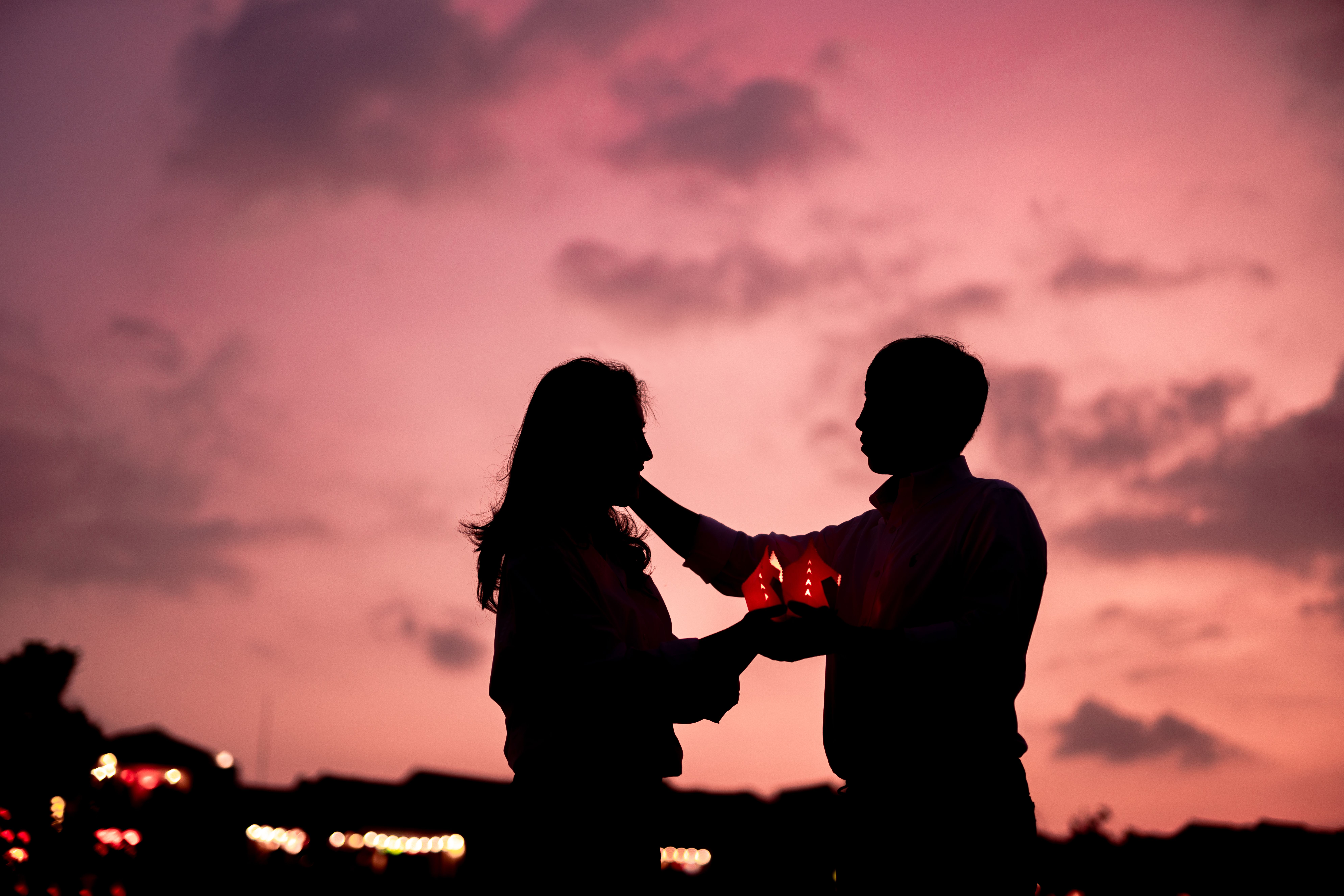 Romantic couple holding lanterns together at sunset, evoking affection and connection